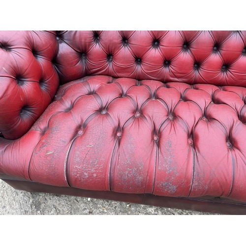 111 - A red leather chesterfield three seater sofa with deep buttoned seat.