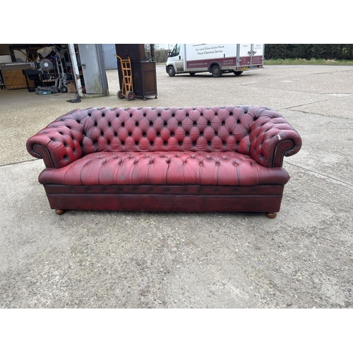 111 - A red leather chesterfield three seater sofa with deep buttoned seat.