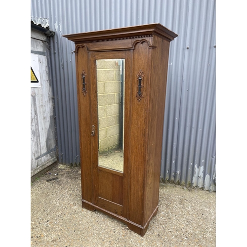 8 - An early 20th century oak mirror door wardrobe with carved details 100x45x196