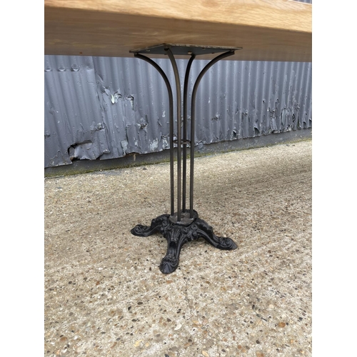 86 - A large light oak dining table with two ornate cast iron supports 82x240