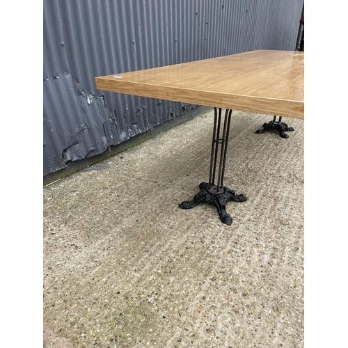 86 - A large light oak dining table with two ornate cast iron supports 82x240