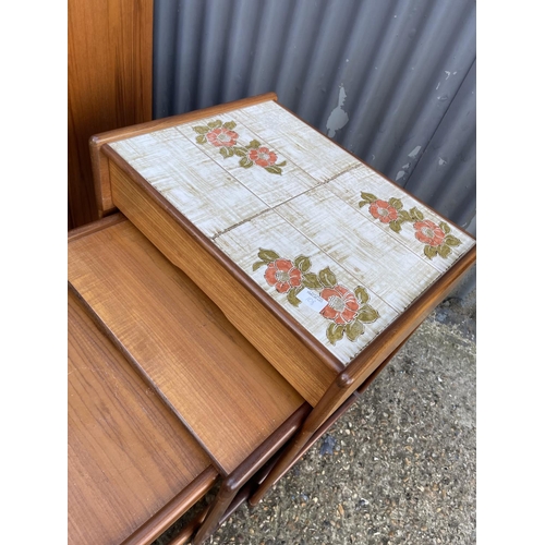 108 - A mid century teak tile top sideboard / bookcase together with a teak tile top nest of three with dr... 