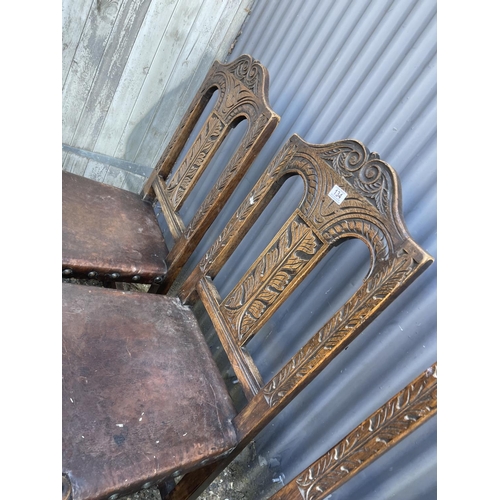 134 - A set of four carved oak dining chairs with leather seats