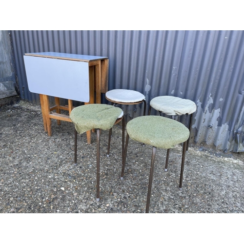 156 - A drop leaf kitchen table together with four stacking stools