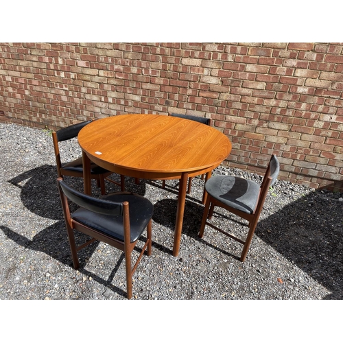 19 - A mid century Macintosh teak extending circular dining table together with four matching chairs with... 