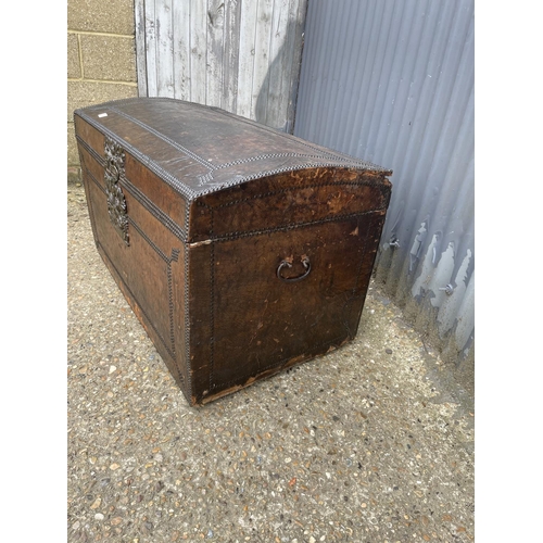 187 - A vintage domed top trunk, leather covered with brass stud work and iron handles 99x56 x 60