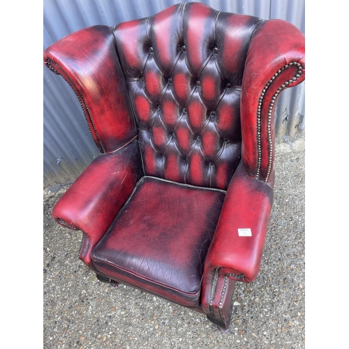 292 - An oxblood red leather chesterfield wing arm chair