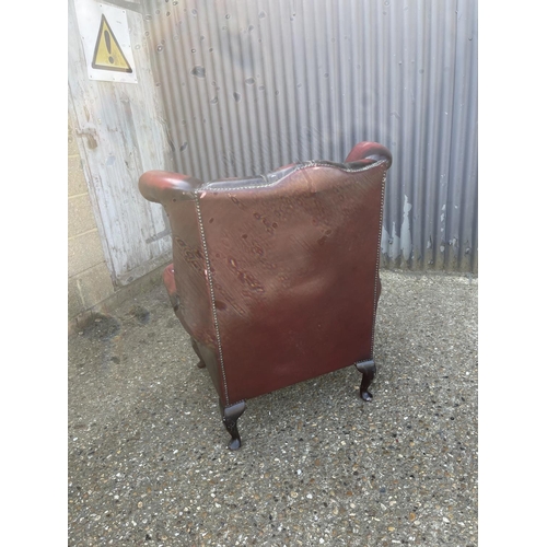 292 - An oxblood red leather chesterfield wing arm chair