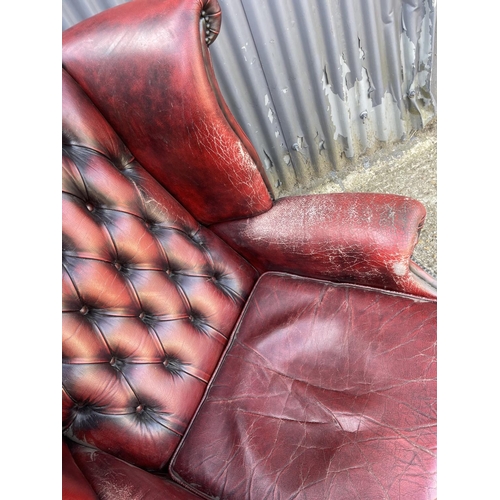 293 - An oxblood red leather chesterfield wing arm chair AF