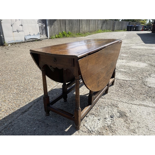 297 - An 18th century oak drop leaf table with drawer to either end 137 diameter