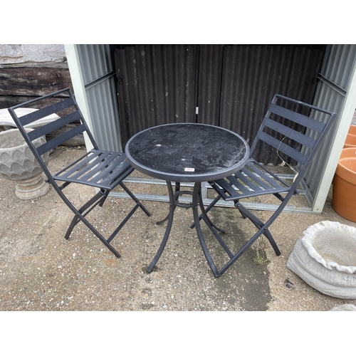 331 - A black metal and glass bistro table with two folding chairs