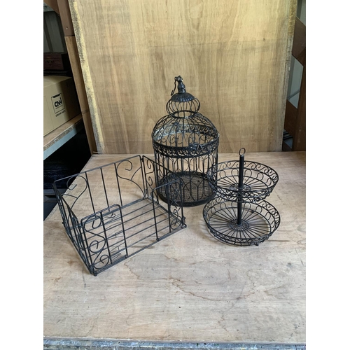 946 - Three pieces black painted metal ware, cage hinge broken and a folding wooden stand