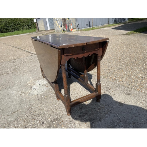 110H - An 18th century oak drop leaf table with drawer to either end 137 diameter