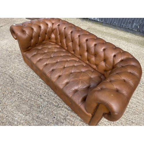 30 - A tan brown leather three seater chesterfield sofa with deep buttoned seat