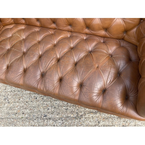 30 - A tan brown leather three seater chesterfield sofa with deep buttoned seat