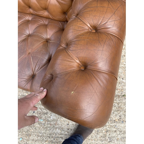 30 - A tan brown leather three seater chesterfield sofa with deep buttoned seat