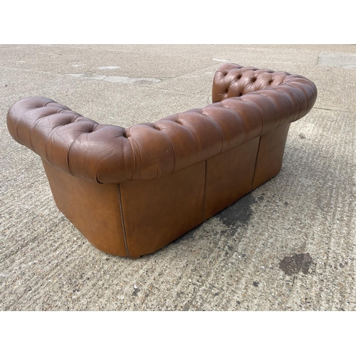 30 - A tan brown leather three seater chesterfield sofa with deep buttoned seat