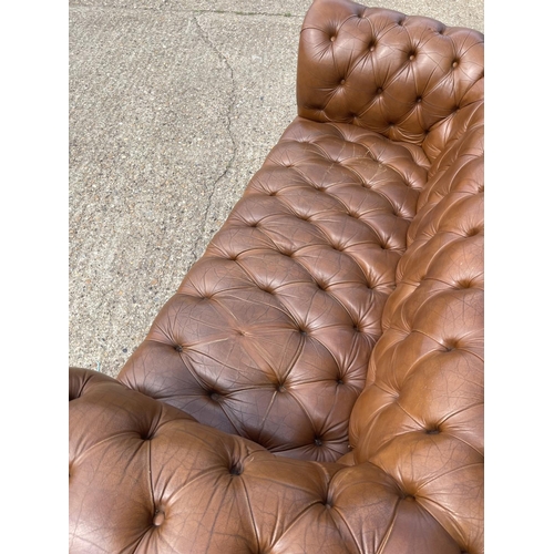 30 - A tan brown leather three seater chesterfield sofa with deep buttoned seat