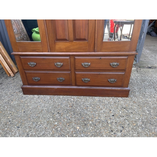 43 - A mahogany double wardrobe on four drawer base with carved central panel 133x48x210