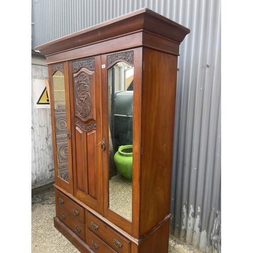 43 - A mahogany double wardrobe on four drawer base with carved central panel 133x48x210