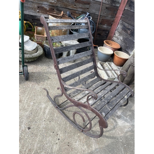 441 - A vintage ornate iron framed garden rocking seat with hardwood slatted seat