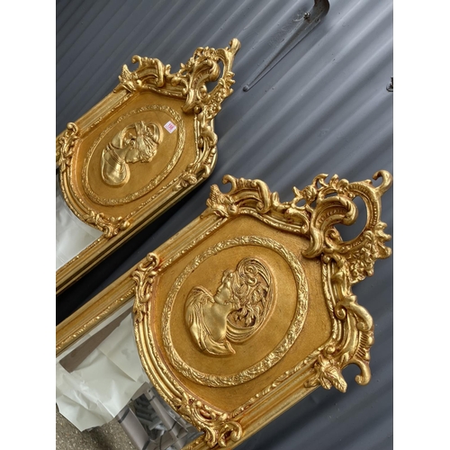 110 - A pair of large ornate gold gilt mirrors decorated with ladies facing each other 180x50 each