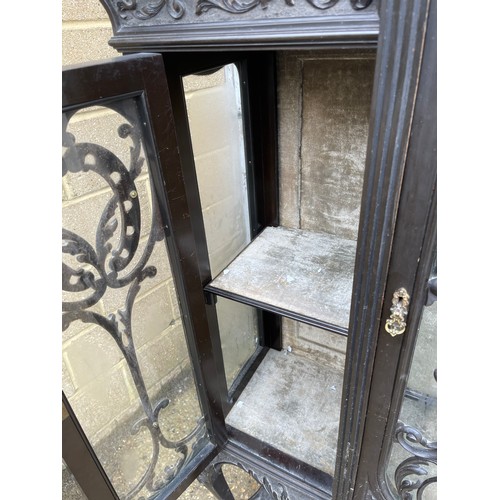 100A - An edwardian glazed display cabinet with creaping death carved decoration