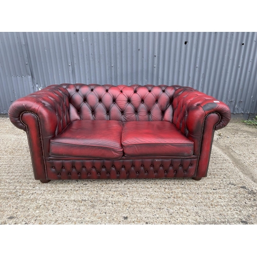 178 - An oxblood red leather chesterfield two seater sofa