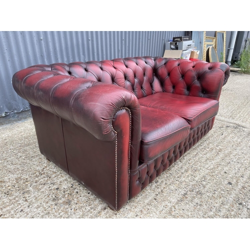 178 - An oxblood red leather chesterfield two seater sofa