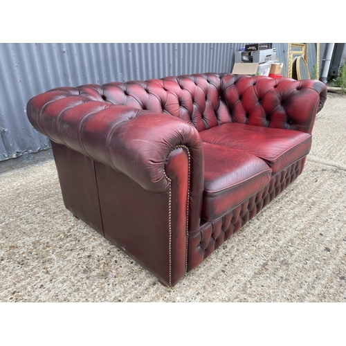 178 - An oxblood red leather chesterfield two seater sofa