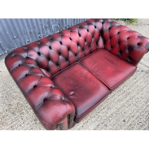 178 - An oxblood red leather chesterfield two seater sofa