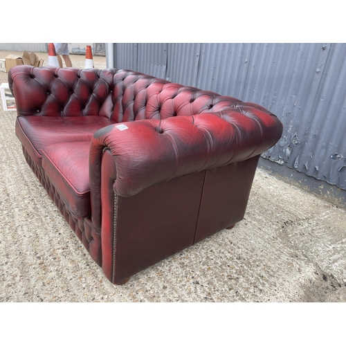 178 - An oxblood red leather chesterfield two seater sofa