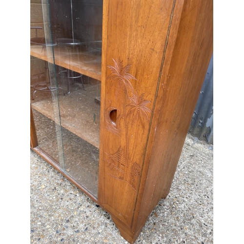 195 - An oriental hardwood cabinet with glazed central section and two carved doors  118x42x118