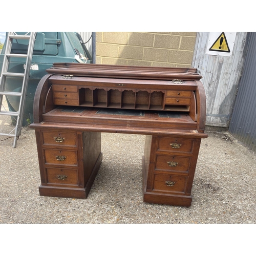 70 - An Edwardian cylinder top desk with dickens style writing surface and fitted interior and drawers