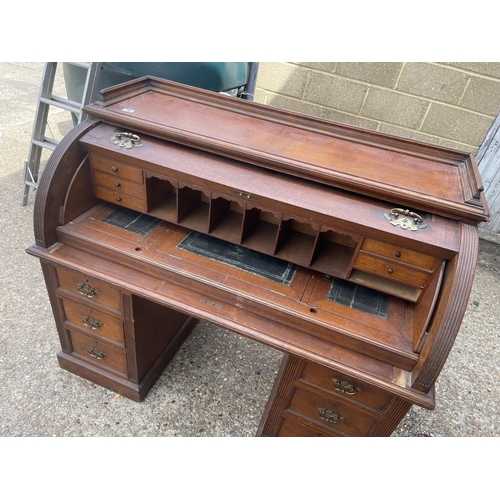 70 - An Edwardian cylinder top desk with dickens style writing surface and fitted interior and drawers