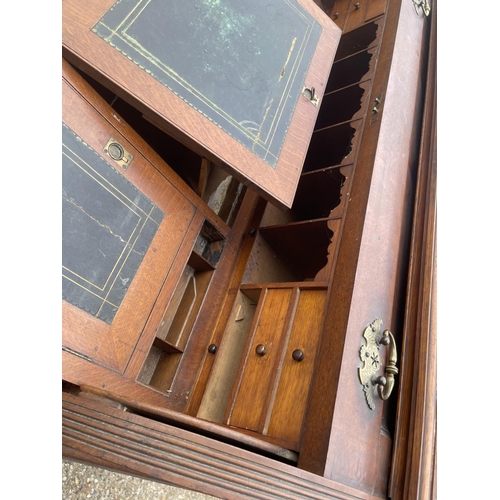 70 - An Edwardian cylinder top desk with dickens style writing surface and fitted interior and drawers