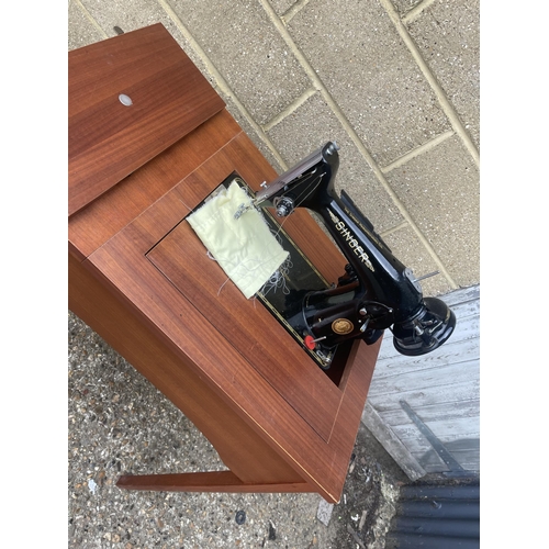 135 - A teak sewing machine table fitted with singer machine, pedal and accessories