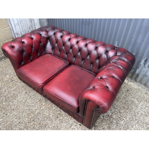 165 - A red leather chesterfield two seater sofa 160cm wide