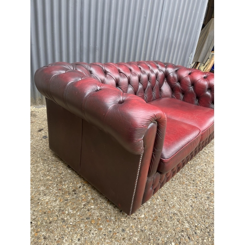 165 - A red leather chesterfield two seater sofa 160cm wide