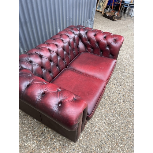 165 - A red leather chesterfield two seater sofa 160cm wide