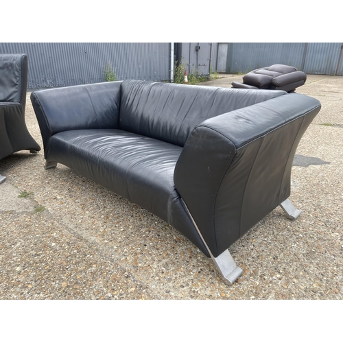 217 - A designer black leather sofa, armchair and stool by ROLF BENZ