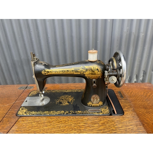 238 - An oak cased singer sewing machine table with cast iron base