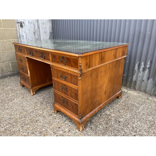 252 - A reproduction yew wood twin pedestal partners desk with drawers to the front and cupboards to the r... 