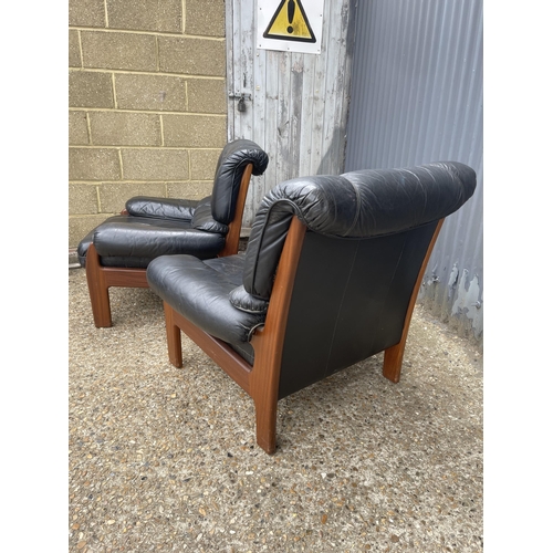 296 - A pair of mid 20th century teak framed armchairs with black leather seats