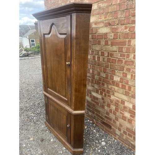 9 - An antique oak two section country house corner cupboard fitted with shelves 100cm wide