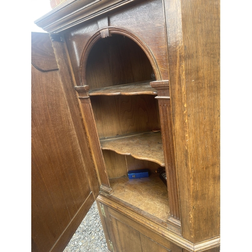 9 - An antique oak two section country house corner cupboard fitted with shelves 100cm wide