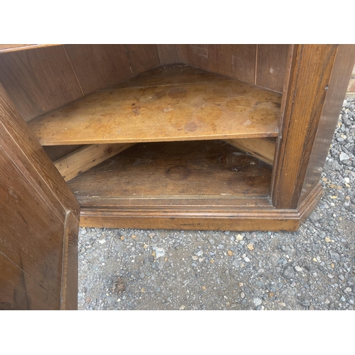 9 - An antique oak two section country house corner cupboard fitted with shelves 100cm wide