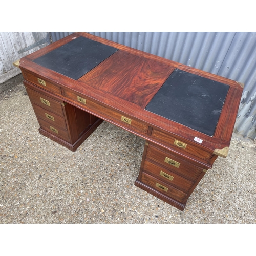 90 - A hardwood twin pedestal desk with brass mounts, military style brass handles and black leather surf... 