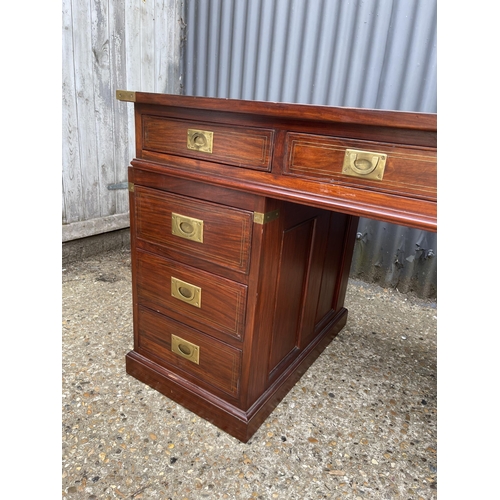 90 - A hardwood twin pedestal desk with brass mounts, military style brass handles and black leather surf... 