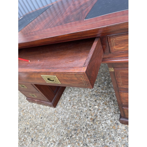 90 - A hardwood twin pedestal desk with brass mounts, military style brass handles and black leather surf... 